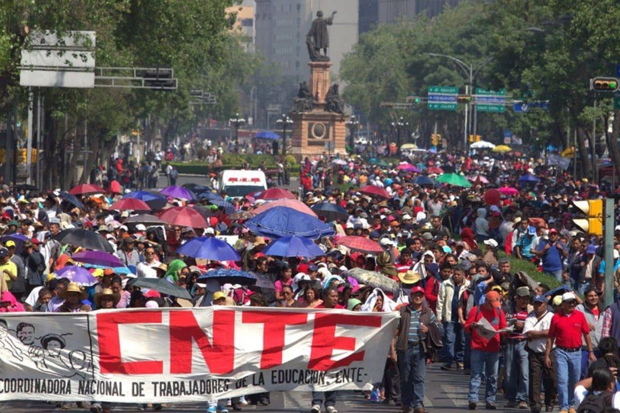 La Coordinadora Nacional de Trabajadores de la Educación (CNTE) convocó a una movilización nacional y a un paro de 24 horas para mañana, miércoles 30 de octubre. La protesta tiene como objetivo exigir la abrogación de la reforma educativa-laboral de 2013 implementada durante el gobierno de Enrique Peña Nieto, que solo fue parcialmente modificada en 2019 bajo la administración de Andrés Manuel López Obrador. ¿Cuáles son las exigencias de la CNTE? Mediante un pronunciamiento frente a la Secretaría de Educación Pública (SEP), dirigentes de las secciones 7, 9, 18 y 22, que representan a maestros de Chiapas, Ciudad de México, Michoacán y Oaxaca, pidieron la eliminación del régimen de excepción laboral estipulado en el artículo 3° constitucional y de la ley del ISSSTE de 2007. Además, señalaron que la Ley del Sistema para la Carrera de las Maestras y Maestros (SICAMM) y su unidad administrativa, el USICAMM, contradicen los principios laborales al regular procesos de ingreso, promoción y reconocimiento, lo cual calificaron como una contradicción legal. Dentro de un boletín informativo, la CNTE reafirmó su compromiso con la defensa de la educación pública, los derechos laborales y la independencia política, reiterando su rechazo hacia cualquier actor que, desde su perspectiva, sirva a intereses estatales. ¿A qué hora y dónde será la movilización de la CNTE? La concentración comenzará a las 10:00 horas en el Ángel de la Independencia y avanzará hacia Palacio Nacional. Los profesores esperan ser atendidos, posteriormente, en una mesa de diálogo con la presidenta Claudia Sheinbaum. Entre sus demandas, también figuran un aumento salarial del 100% al sueldo base y una mejora integral de las condiciones laborales. Con esta movilización, la CNTE busca presionar por una “justicia social y laboral”. Ya que la consideran esencial para el gremio educativo, en la que esperan se atiendan las necesidades históricas del magisterio mexicano.